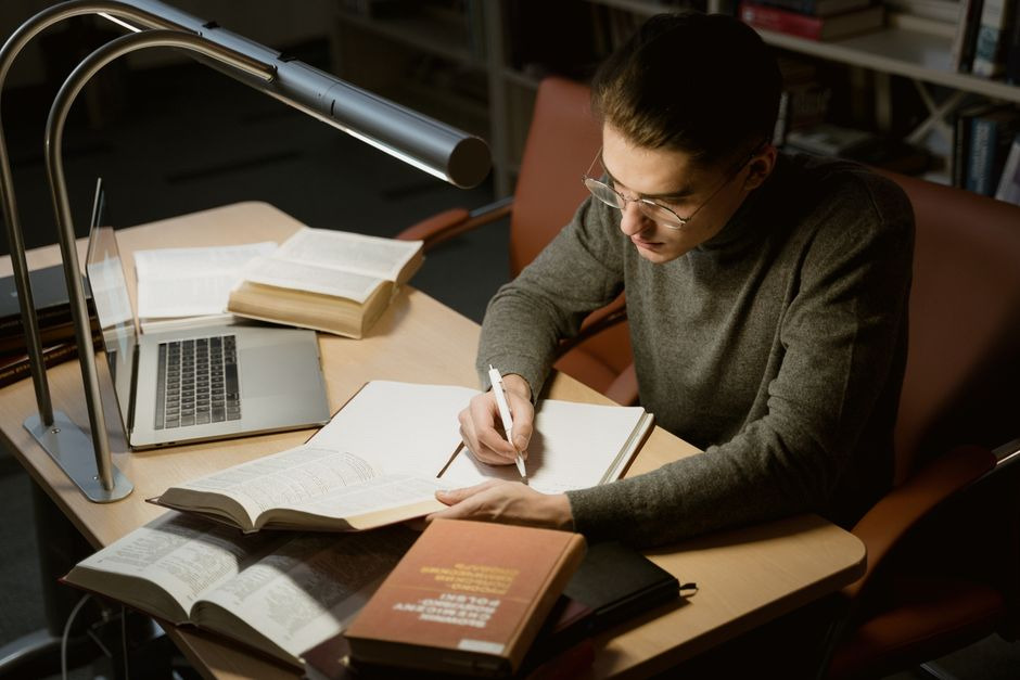 Law student studying with books, notes, and a laptop at a library desk