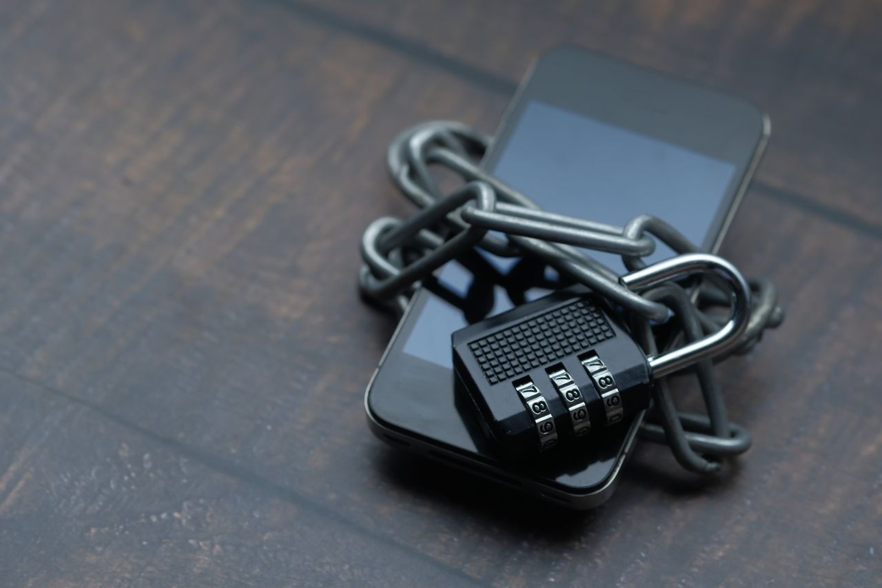 Smartphone wrapped in a metal chain and secured with a combination padlock