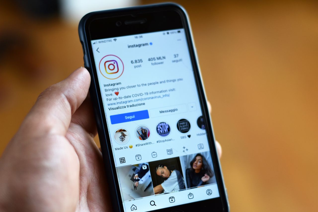 Person holding a smartphone displaying an Instagram profile