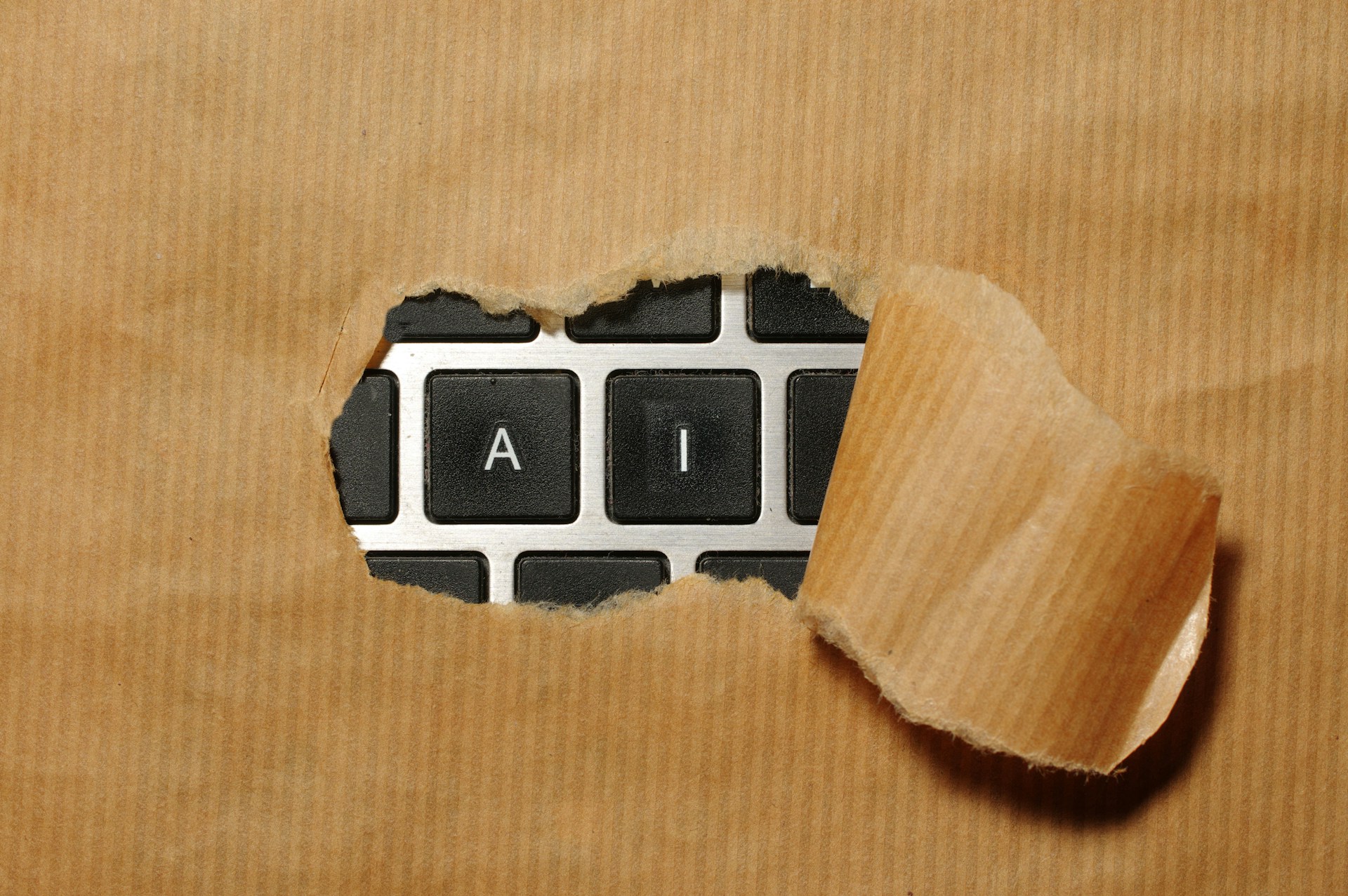 Keyboard with AI keys visible through torn brown paper