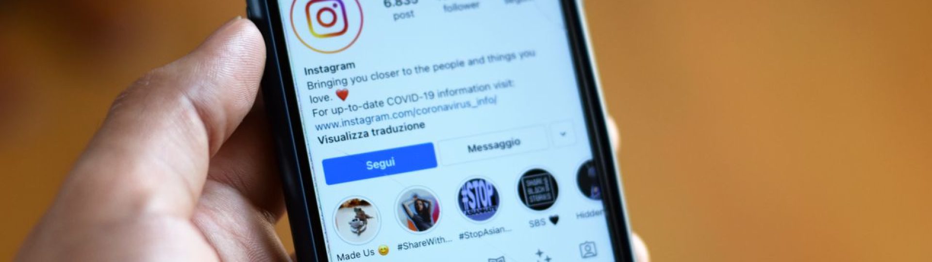 Person holding a smartphone displaying an Instagram profile