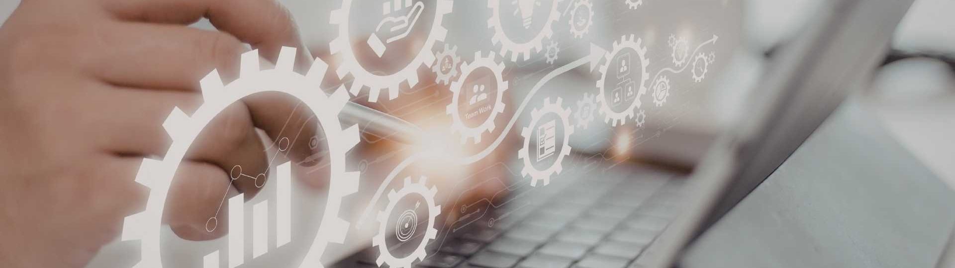 Hand using a tablet keyboard with translucent gear and analytics icons overlayed.