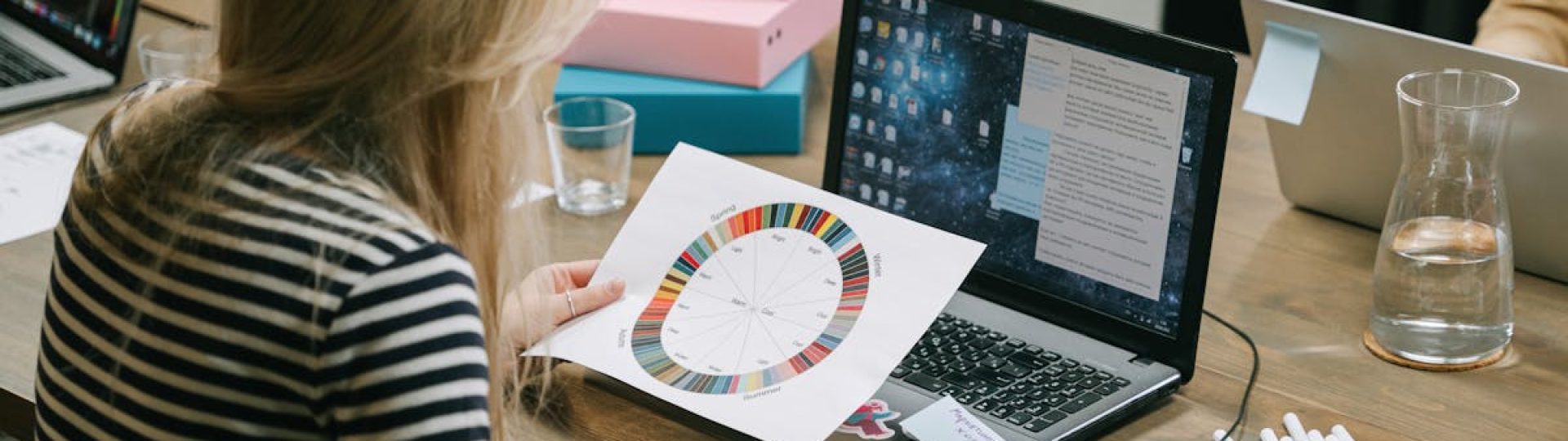 A woman studying a color wheel on a laptop during a work session in a modern office.
