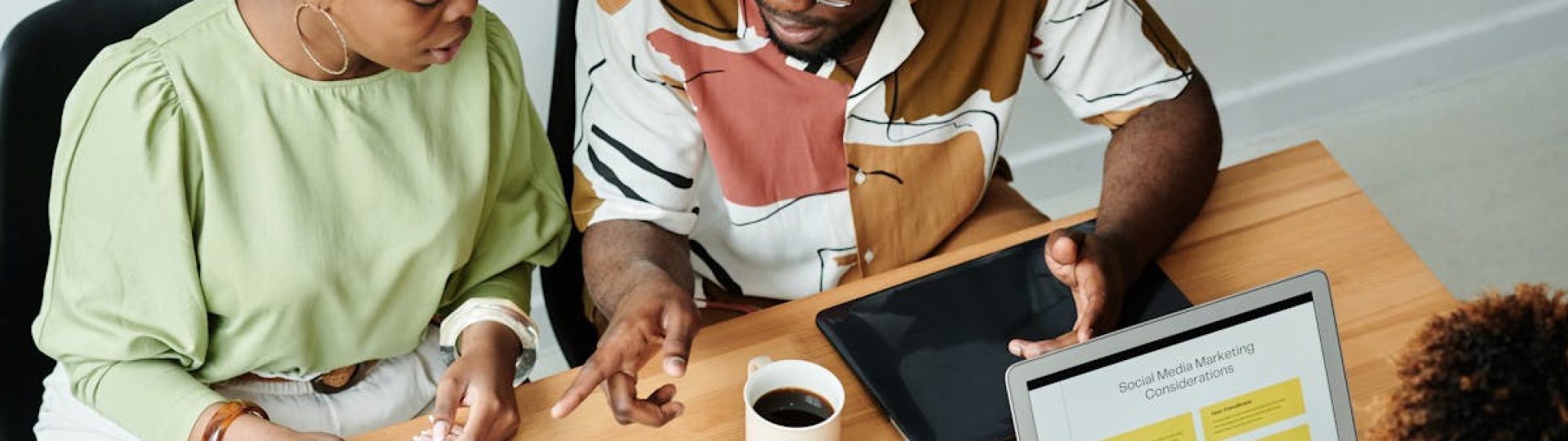 Three colleagues collaborate over marketing documents and a laptop in a modern office setting.