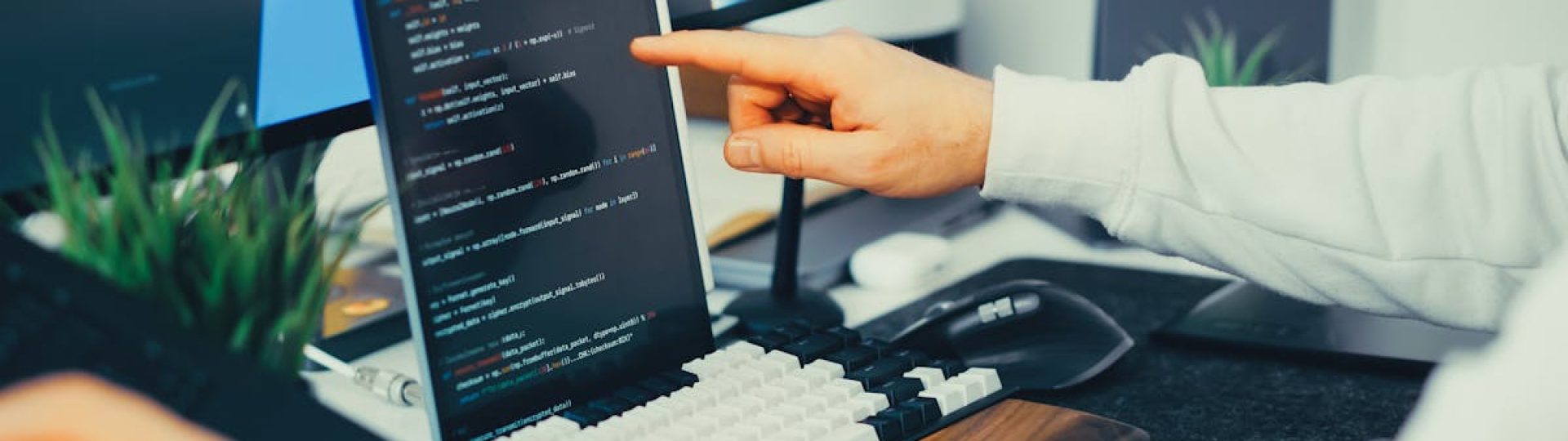 A programmer working on code with a laptop and monitor setup in an office.