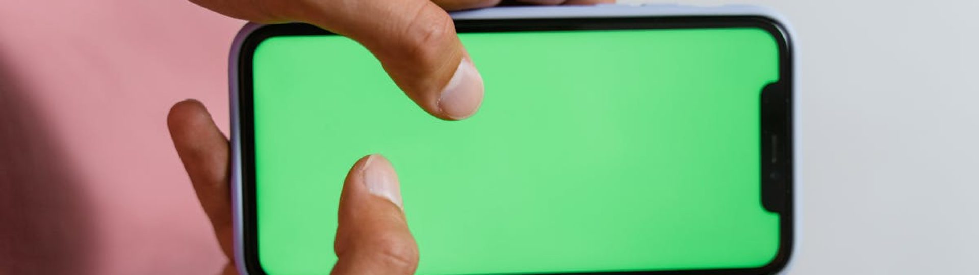 Hands holding smartphone with a green screen, suitable for digital content overlay.