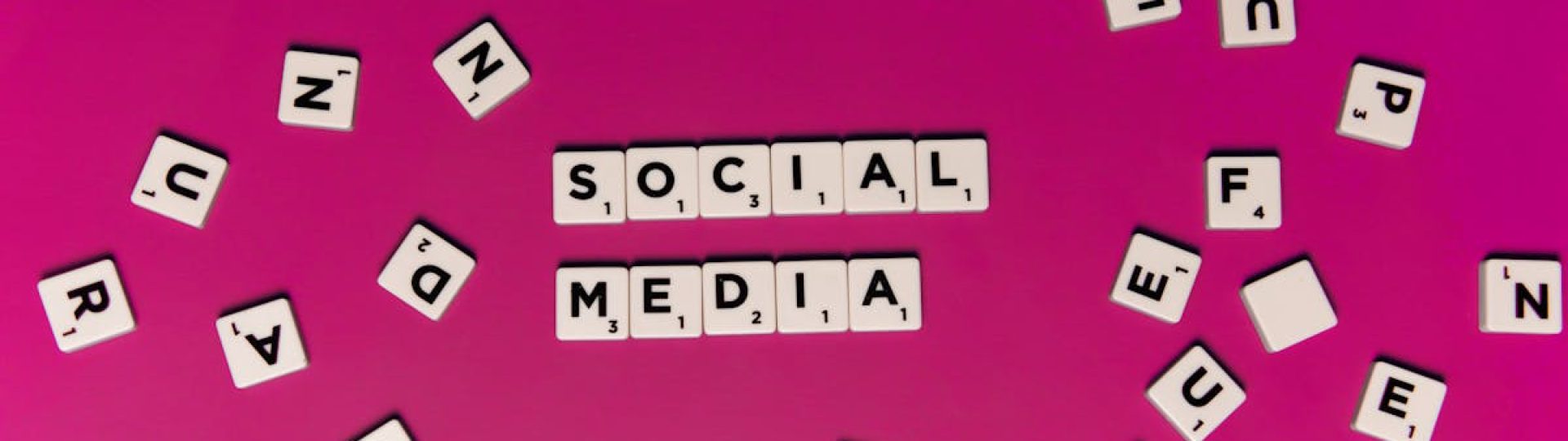 Alphabet tiles forming 'Social Media' on a vibrant pink background, perfect for digital marketing themes.