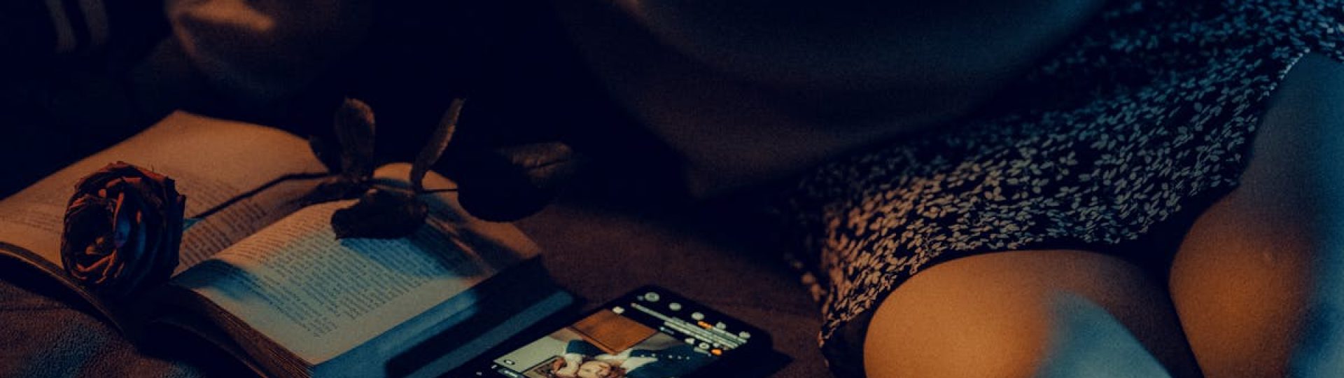 Cozy scene with a book, smartphone, and low lighting conveying a relaxed evening at home.