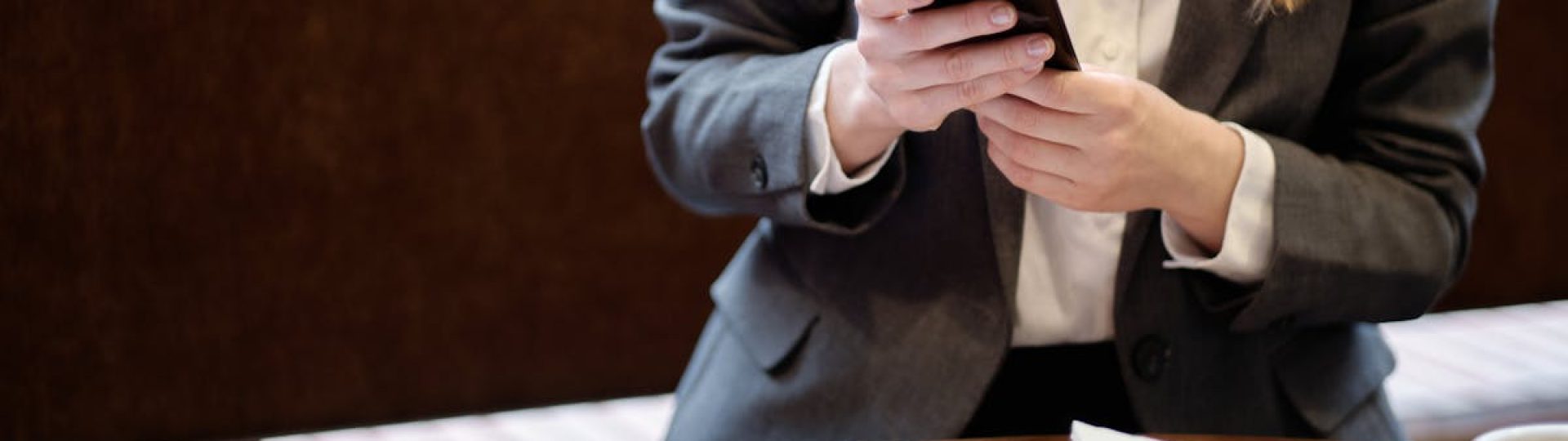Businesswoman using smartphone in a café, with slice of cake and coffee.
