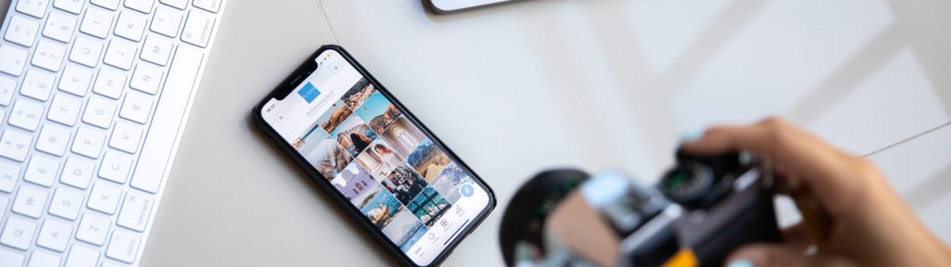 Person using vintage camera with smartphone and laptop in creative setup.