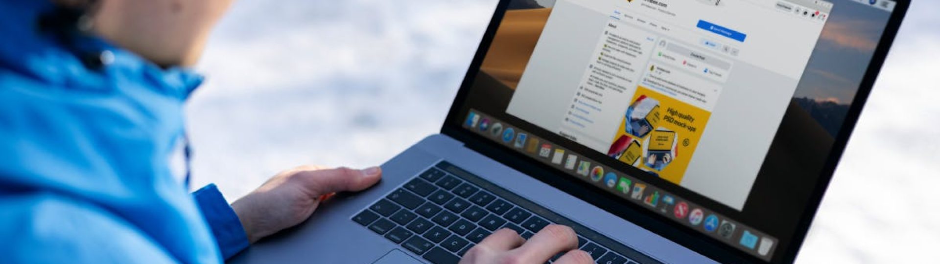 Close-up of individual using laptop outdoors in snow, browsing social media.