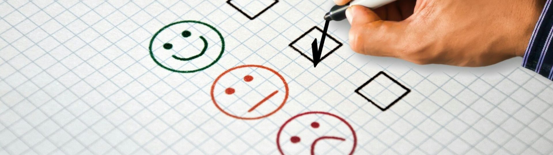 Hand drawing a check mark next to customer feedback icons showing happy, neutral, and unhappy faces.