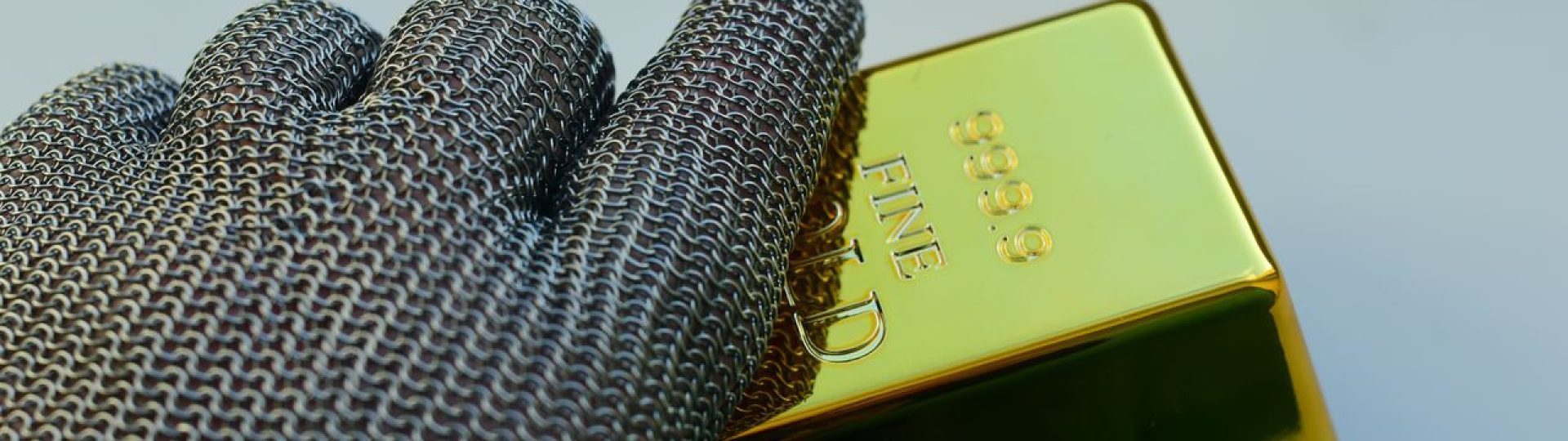 Gloved hand holding a gold bar