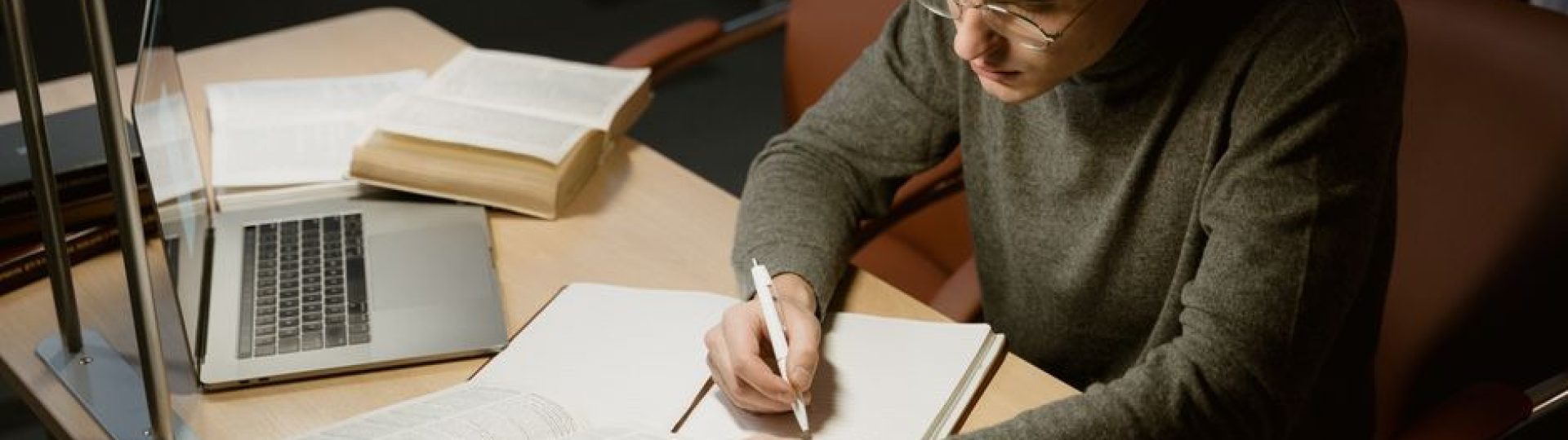 Law student studying with books, notes, and a laptop at a library desk