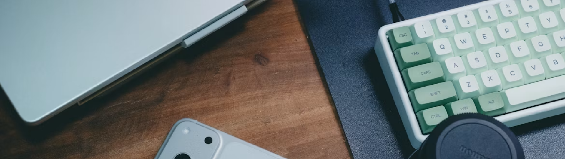 Creator workspace with smartphone, laptop, keyboard, and camera lens for social media video content
