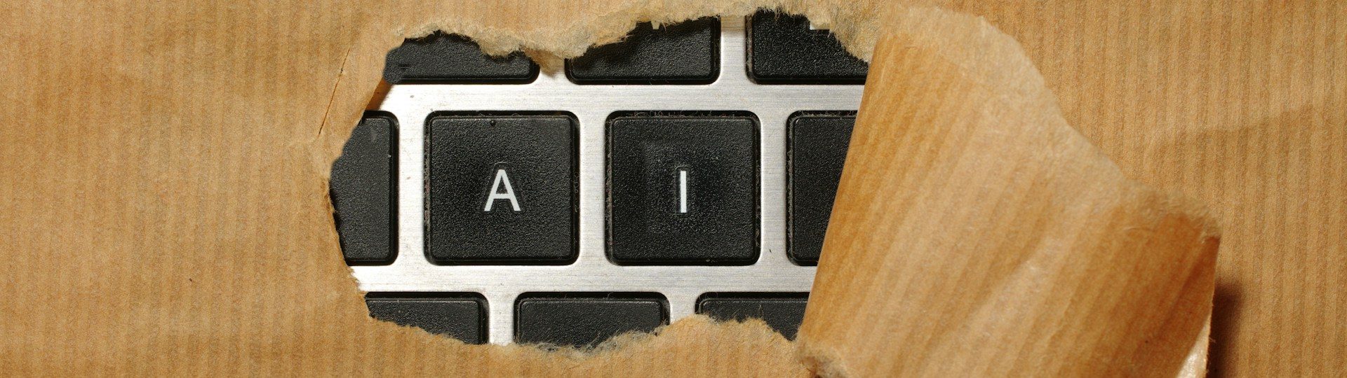 Keyboard with AI keys visible through torn brown paper