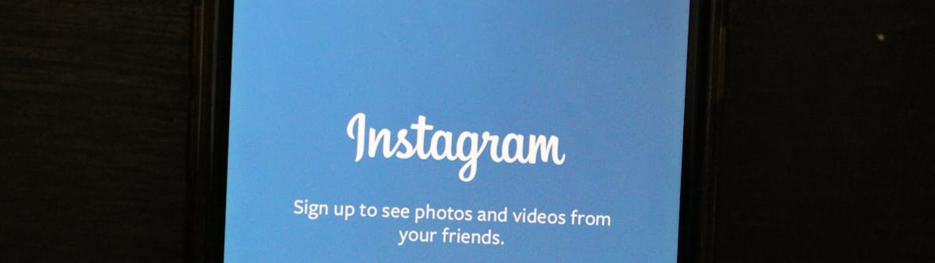 Close-up of a smartphone displaying the Instagram app welcome screen, inviting users to sign up.