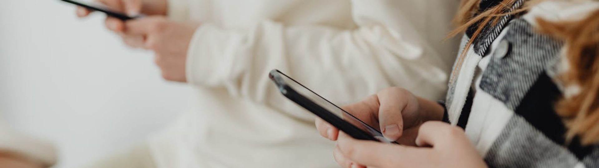 Close-up of two people using smartphones indoors, highlighting technology and communication.