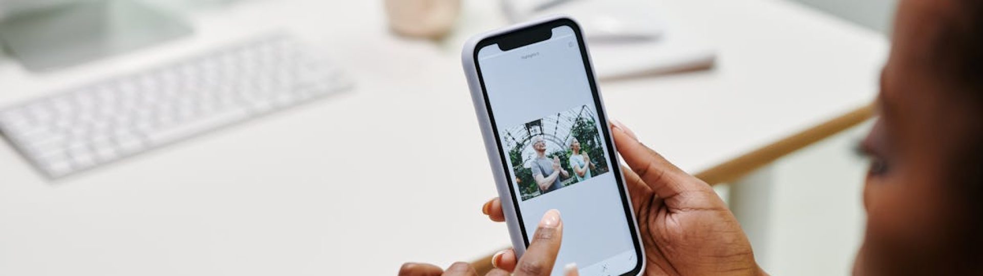 Close-up of hands using a smartphone at a desk with a computer. Ideal for tech and lifestyle content.