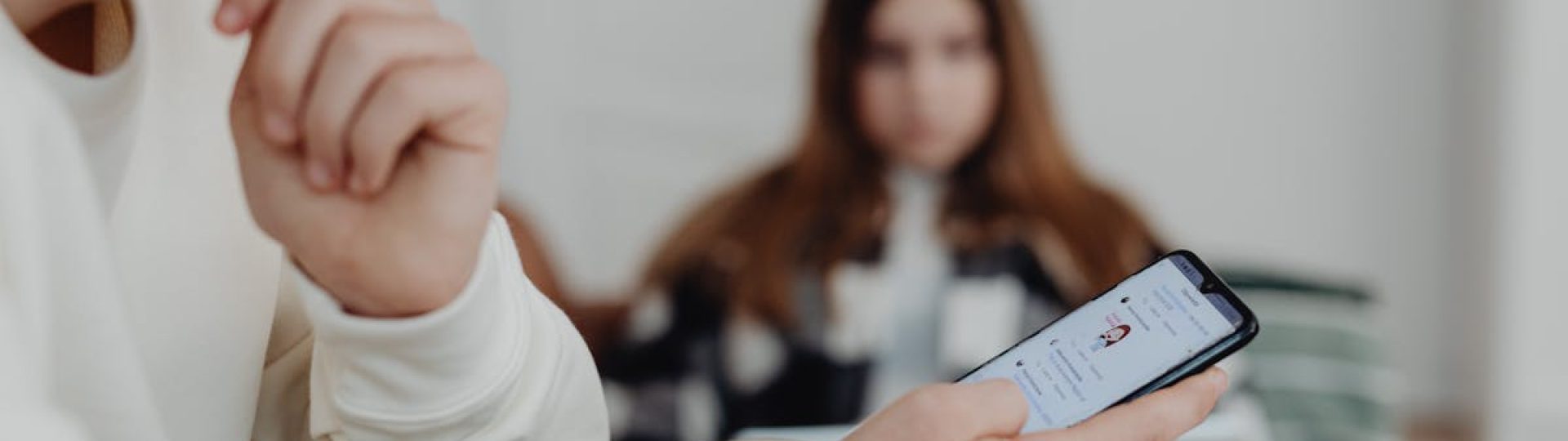 Teens using smartphones indoors with a blurred background, suggesting social media engagement.
