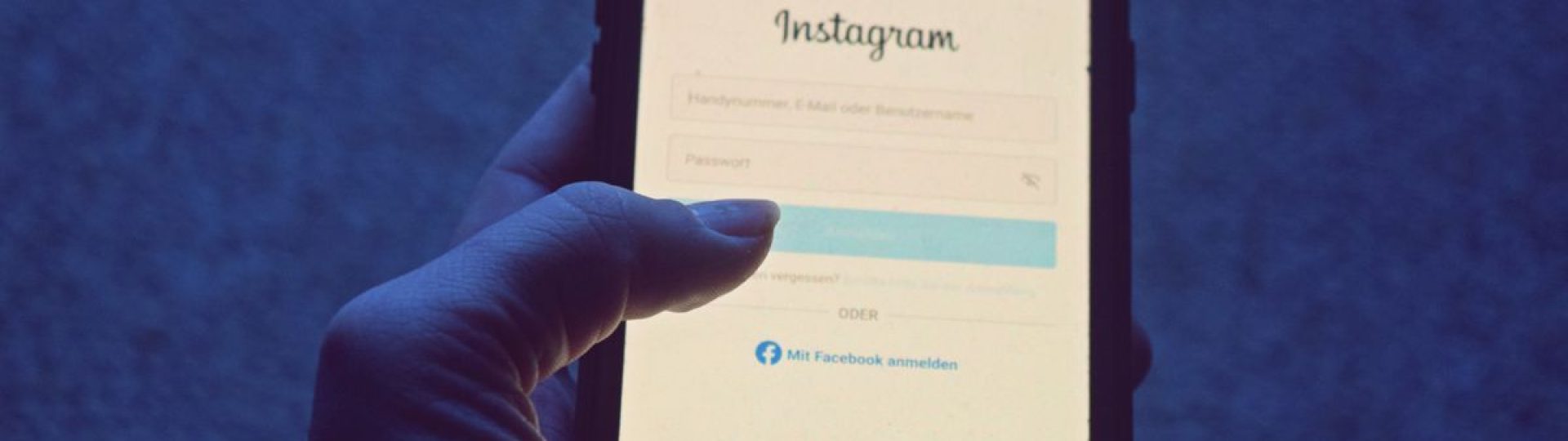 Close-up of a hand holding a smartphone displaying the Instagram login screen.