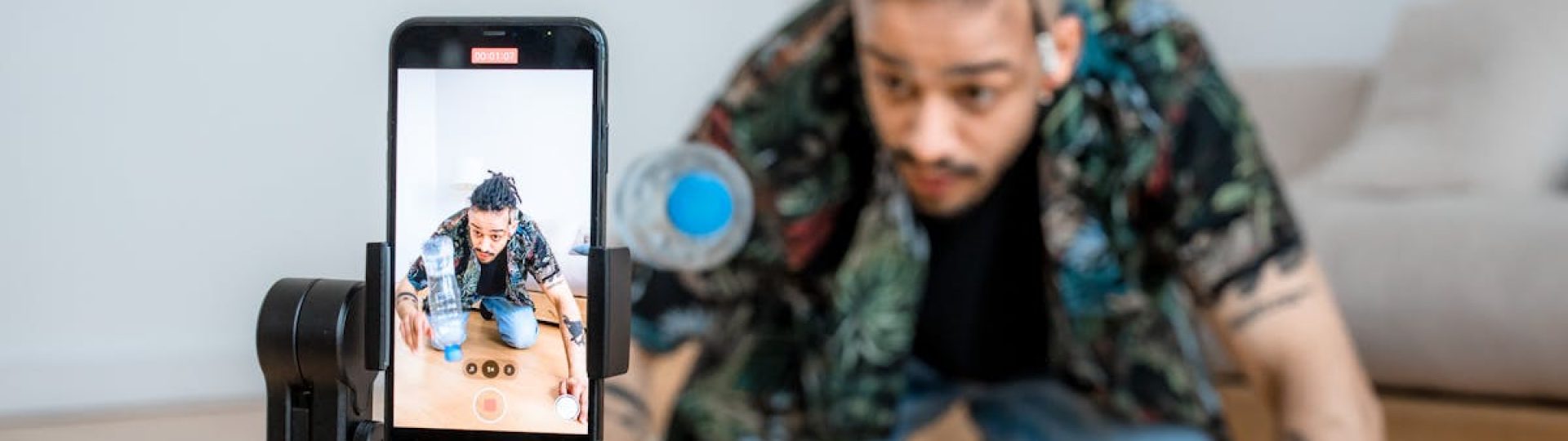 Man filming creative content with smartphone on gimbal indoors.