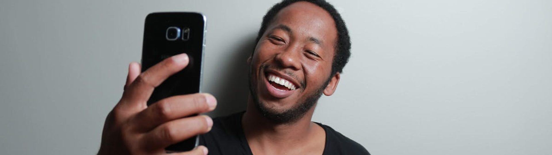 Happy man capturing a cheerful selfie with smartphone indoors.