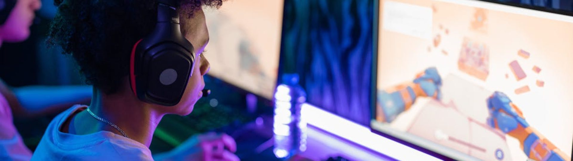 Teen gamers engrossed in online computer game in a vibrant, modern gaming room.
