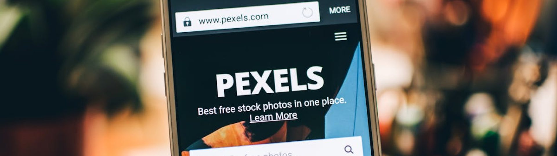 A close-up view of a smartphone displaying the Pexels website screen for stock photo searches.