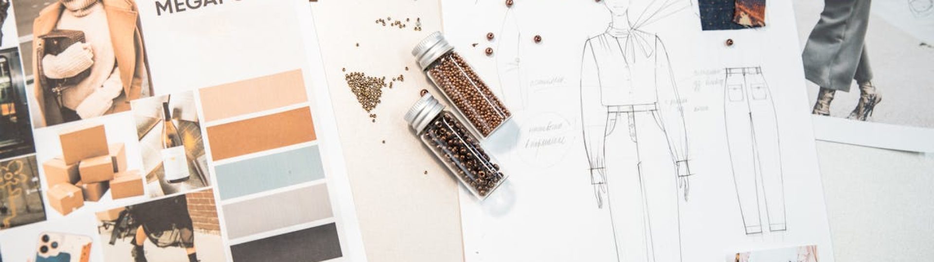 Creative fashion workspace featuring design sketches, mood boards, and beads on a desk.