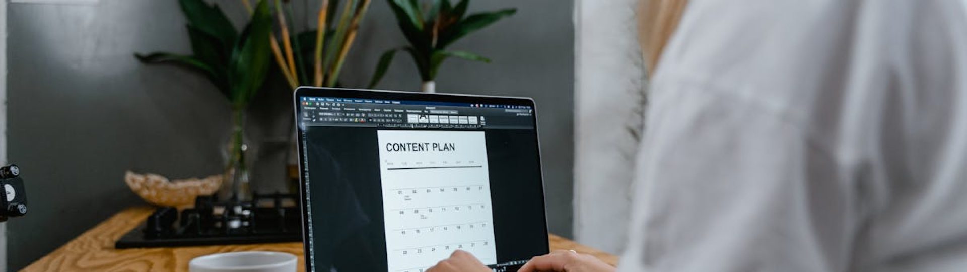Focused woman typing on laptop while creating a content plan in a modern workspace.
