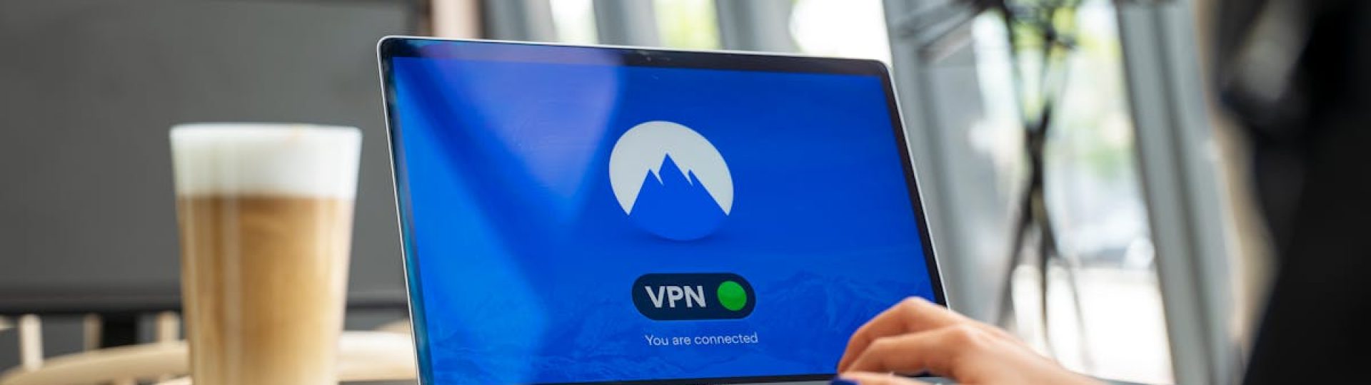 A person using a laptop with a VPN connection in a modern cafe setting, showcasing remote work and internet security.