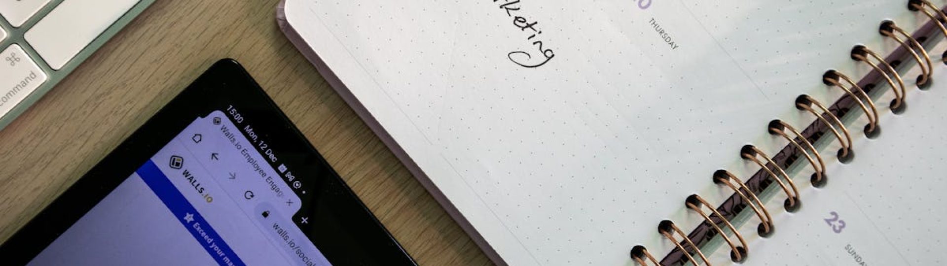 Top view of a notebook, tablet, and keyboard used for social media marketing planning.