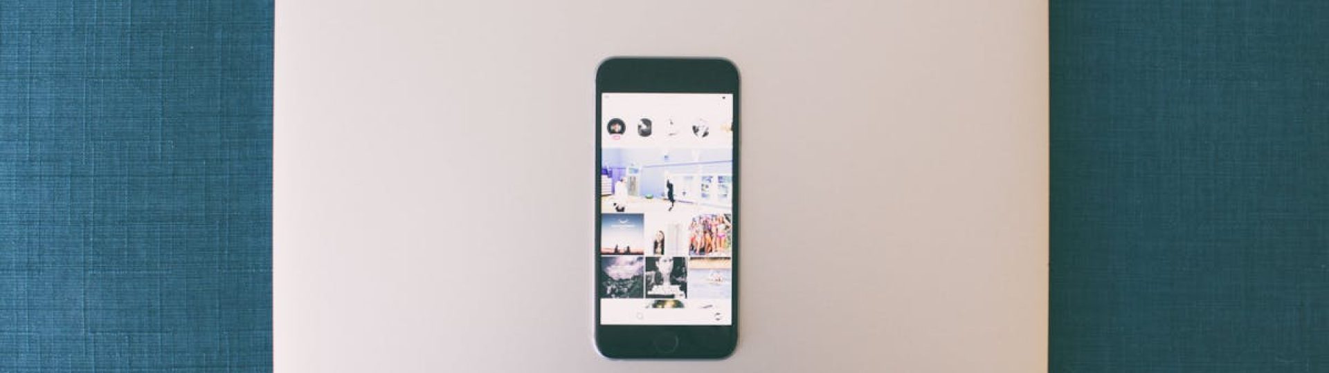 Flat lay of a smartphone on a laptop with social media photos on screen.