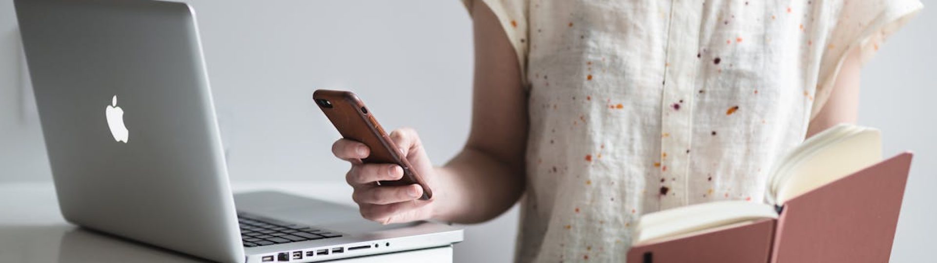 Woman working on a laptop while reading and texting, embodying modern multitasking.