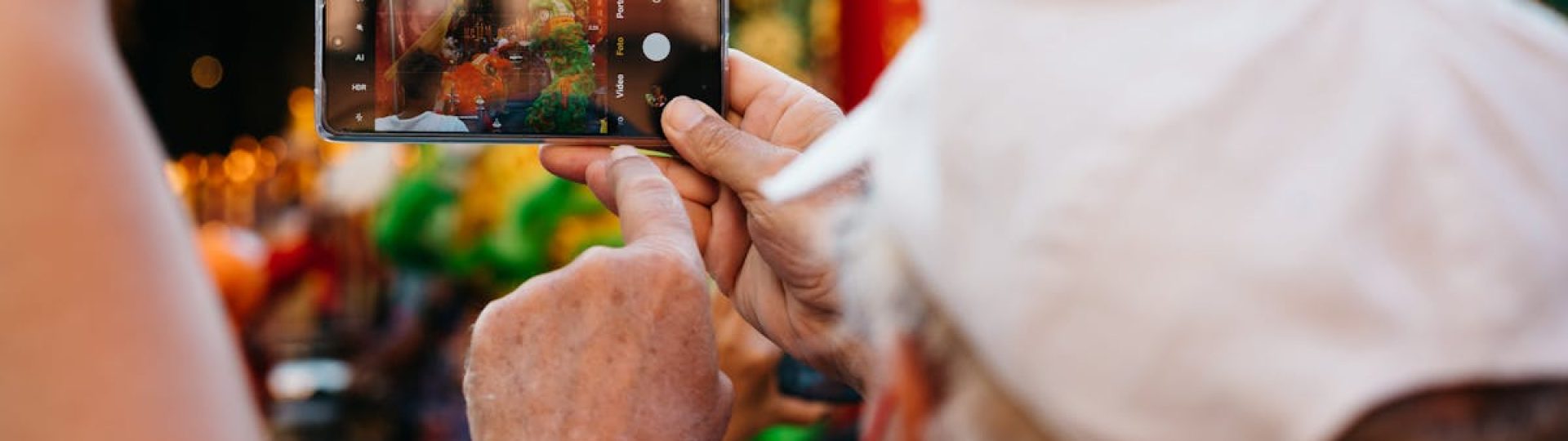 A person captures a vibrant street event with a smartphone, focusing on details and colors.