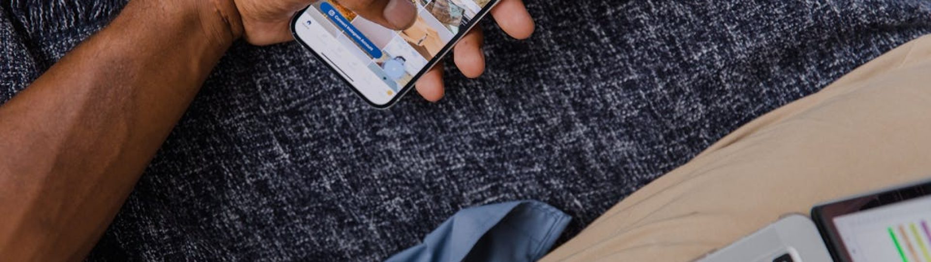 Hand holding smartphone with open laptop, showcasing modern digital lifestyle.