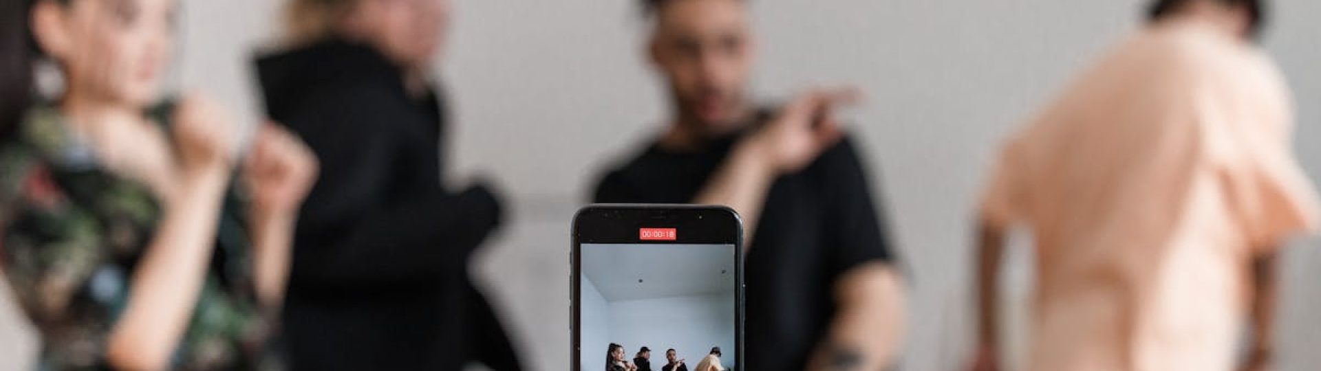 Group of dancers recording performance with smartphone on tripod, capturing trendy dance moves.