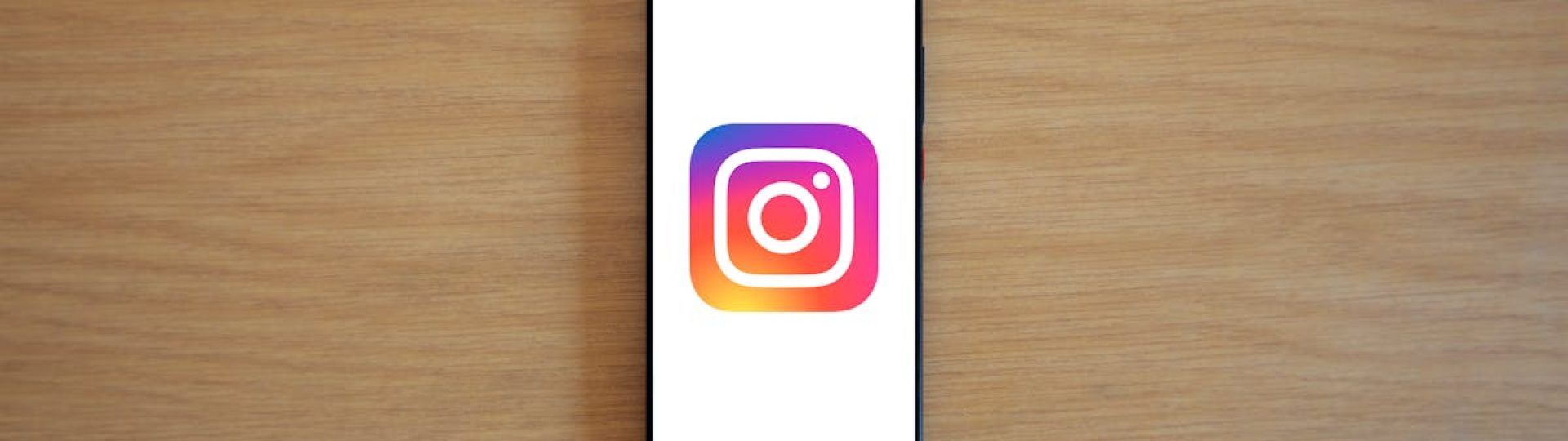A smartphone with the Instagram logo on display, placed on a wooden surface. Perfect for technology and social media themes.