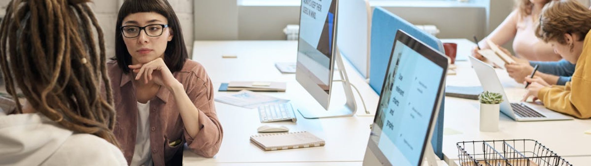 Diverse group of women working together in a modern office setting, fostering teamwork and creativity.